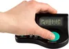 A hand is holding a black digital alarm clock with a green button. Produktbild-Vorschau
