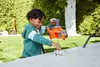 A young boy is playing with a toy helicopter and a small vehicle outdoors on a table. Podgląd zdjęcia produktu