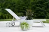 A white lounge chair with two potted plants on a patio. Náhľad obrázku produktu