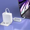 A white power adapter is plugged into a wall socket, connected by a white cable to a laptop. Produktbild-Vorschau