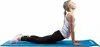 A woman is performing a yoga pose on a blue yoga mat. Produktbild-Vorschau