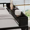 A close-up view of a bed with a shelf attached to the headboard, decorated with candles, a diffuser, and a lamp. Produktbild-Vorschau