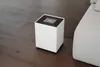 A white humidifier sits on a wooden floor next to a gray sofa. Náhľad obrázku produktu