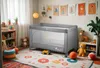 A child's bedroom with a travel crib, toys, and decorations. Podgląd zdjęcia produktu