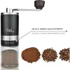 A black manual coffee grinder with a glass container, next to piles of different coffee grinds and whole beans. Anteprima dell’immagine prodotto