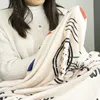A person is holding a blanket with a printed design. Produktbild-Vorschau