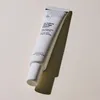 A white tube of anti-aging cream is placed diagonally on a light-colored surface, casting a shadow. Náhľad obrázku produktu