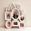 A white multi-photo frame collage shaped like the word 'FAMILY' mounted on a wall. Produktbild-Vorschau