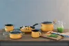 A collection of yellow cookware and kitchen accessories arranged on a wooden surface. Podgląd zdjęcia produktu
