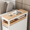 A narrow side table with a wooden top and white frame, placed next to a sofa. A magazine and a cup of coffee are on the table. Produktbild-Vorschau