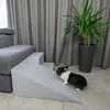 A rabbit is climbing on a grey pet ramp next to a sofa and a plant. Anteprima dell’immagine prodotto