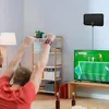 Schwarze Flachbild-TV-Antenne an einer weißen Wand über einem Fernseher montiert, mit einer Person, die Fußball schaut Productafbeelding-voorbeeld