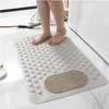 A person's feet are standing on a beige bath mat in a bathroom. Produktbild-Vorschau