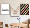 Three framed pictures hang on a wall above a wooden table with a vase of blue flowers. Produktbild-Vorschau