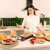 A woman is preparing breakfast in a kitchen, using a toaster. Produktbild-Vorschau