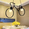 A black bicycle-shaped pendant light hangs above a dining table set for a meal. Podgląd zdjęcia produktu