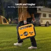 A person is carrying a yellow generator in a grassy outdoor setting with tents and a camper van in the background. Podgląd zdjęcia produktu
