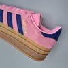 A close-up view of the side of a pink Adidas Gazelle Bold sneaker with navy blue stripes and a stacked brown sole. Náhled obrázku produktu