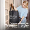 A woman is holding a black storage bag with a logo and text on it, standing in front of a closet. Produktbild-Vorschau