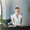 A woman is working on a laptop while sitting in an office chair. Produktbild-Vorschau