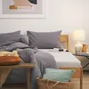 A cozy bedroom scene with a neatly made bed, pillows, and a bedside table with a lamp and decorative items. Produktbild-Vorschau