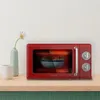 A red retro-style microwave oven is shown on a wooden shelf, with a vase of flowers and a cup next to it. Anteprima dell’immagine prodotto