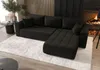 A modern living room scene featuring a black sectional sofa with a fireplace in the background. Produktbild-Vorschau