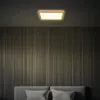 A modern bedroom with a wooden framed LED ceiling light illuminating a wall with vertical paneling and a bed with pillows. Produktbild-Vorschau