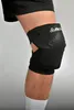 A close-up of a person's knee wearing a black knee brace. Anteprima dell’immagine prodotto