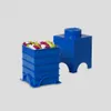 Two blue LEGO storage bricks are shown against a light gray background. One brick is a container filled with colorful confetti-like pieces, and the other is a solid brick. Produktbild-Vorschau