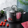 A stainless steel pot with a glass lid sits on a black countertop, surrounded by cherry tomatoes and a red and white checkered cloth. A bottle of olive oil is visible on the left, and greenery is in the background. Produktbild-Vorschau