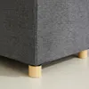 Close-up of the bottom corner of a gray fabric storage ottoman, showing its wooden legs. Anteprima dell’immagine prodotto