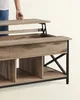 A person's hand is lifting the top of a lift-top coffee table, revealing storage space. Produktbild-Vorschau