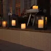 Several LED candles are placed on a tiled surface next to a wooden ledge, with lanterns and a stool in the background. Podgląd zdjęcia produktu