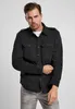 A man wearing a black shirt and grey jeans, posing against a light gray background. Produktbild-Vorschau