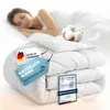 A woman sleeping peacefully under a white duvet, with product tags and a cotton ball prominently displayed. Produktbild-Vorschau