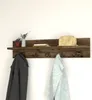 A wooden coat rack with a shelf mounted on a white wall, decorated with a vase of flowers, books, and a handbag. Produktbild-Vorschau