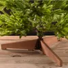 Close-up view of the base of an artificial Christmas tree, showing its green branches and a wooden stand. Podgląd zdjęcia produktu