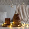 A decorative tray with a vase of dried flowers, a glass candle holder, and a string of fairy lights. Produktbild-Vorschau