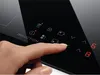 A close-up of a finger interacting with the control panel of an induction cooktop. Voir les images du produit