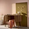 A wooden desk with storage and a stool in a room with pink and olive green walls. Produktbild-Vorschau