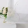 A close-up view of a sheer beige curtain with embroidered wavy pearl patterns, placed next to a vase of white roses. Produktbild-Vorschau