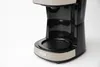 A close-up shot of a black and beige coffee maker against a white background. Náhled obrázku produktu