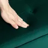 A hand pressing into a tufted green upholstered surface. Náhled obrázku produktu