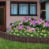 A garden border made of brown wooden stakes is placed in front of a flower bed with pink hydrangeas and yellow flowers, next to a house. Náhled obrázku produktu