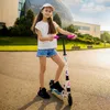 A young girl is standing on a street with a scooter. Podgląd zdjęcia produktu