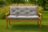 A garden bench with a gray cushion sits on a green lawn with tall grasses and trees in the background. Produktbild-Vorschau