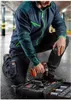A man kneeling in a parking garage, holding a drill and working on a toolbox. Produktbild-Vorschau