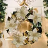 A festive wreath decorated with artificial poinsettias and gold leaves, hanging on a white door. Produktbild-Vorschau