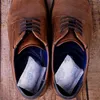 A pair of brown leather shoes with silica gel packets inside. Produktbild-Vorschau